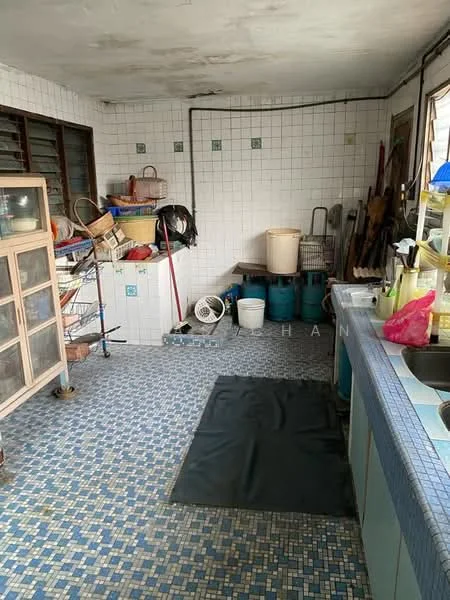 Laundry features: blue mosaic tile flooring, white tiled walls, wooden shelving unit, metal storage rack, various cleaning supplies, plastic buckets, laundry sink, countertop with storage underneath, exposed plumbing, ceiling fan.