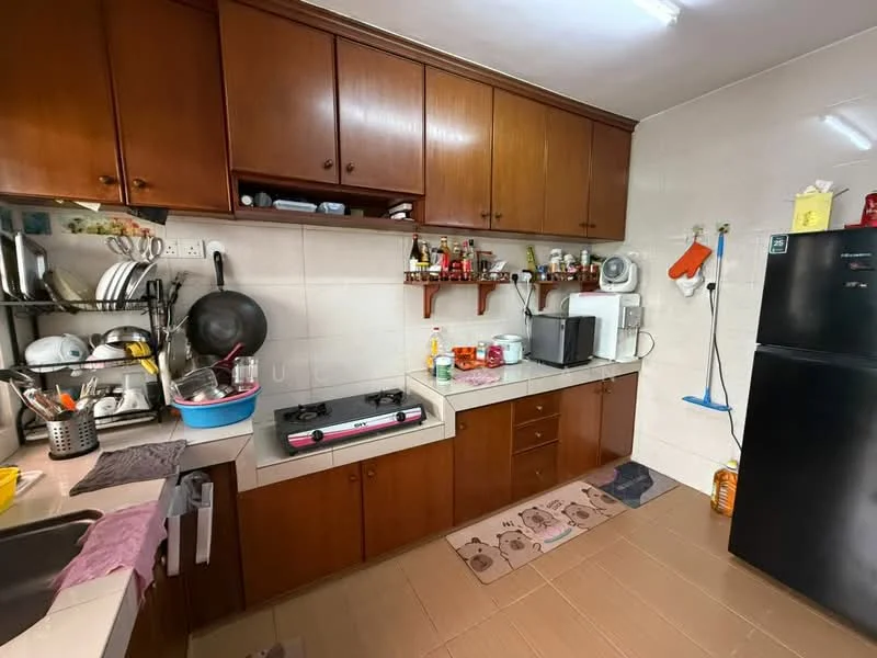 Kitchen features: brown wooden cabinetry, white tiled walls, grey tiled flooring, double-bowl stainless-steel sink, gas stove with two burners, black refrigerator, microwave, kitchen countertop, open shelving, various kitchen utensils, wall-mounted kitchen accessories, decorative kitchen mat; style: functional.