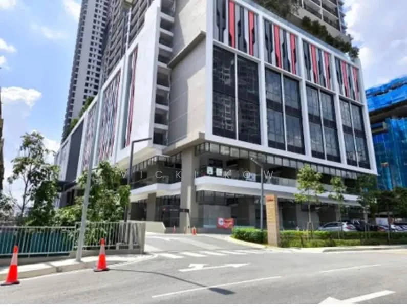 Exterior type: high-rise condominium; features: glass curtain wall, white painted facade, red and black accent panels, multiple storeys, landscaped entrance, driveway with interlocking pavers, surrounded by greenery, visible parking area; style: modern.