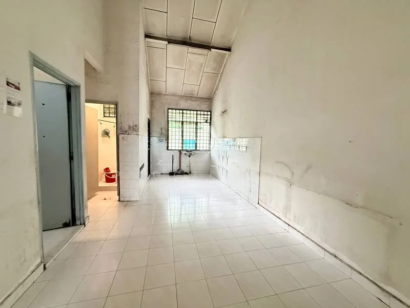 Room features: white painted walls, white tiled flooring, high ceiling, window with metal grille, doorway leading to bathroom, sink, toilet, light fixture, open space layout.