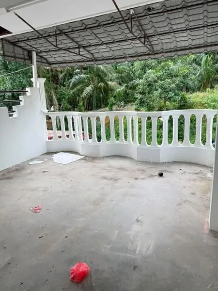 Room features: concrete flooring, white painted walls, covered ceiling, railing with decorative balusters, outdoor view of greenery, open space, no furniture, scattered debris; view: garden.