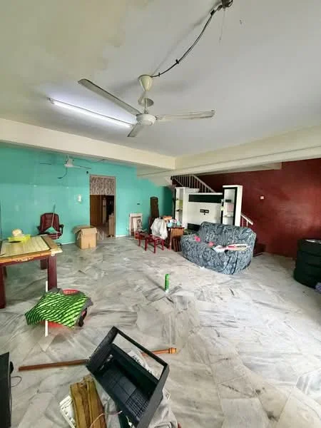Living features: marble flooring, green painted walls, red accent wall, 5-blade ceiling fan, sofa with patterned upholstery, wooden dining table, wooden chairs, staircase in background, boxes and miscellaneous items scattered, open layout.