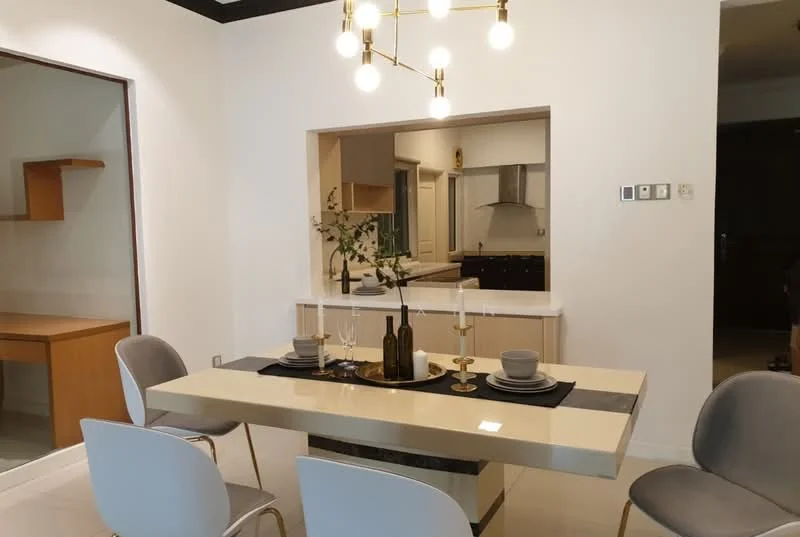 Dining features: rectangular dining table with cream surface, 4 upholstered dining chairs in light grey, chandelier with multiple bulbs, decorative table setting with candles and vases, white painted walls, tile flooring, open kitchen view in background, wall-mounted light switches; style: modern. Room features: wooden shelving unit, kitchen cabinetry visible in background, stainless-steel kitchen appliances visible.