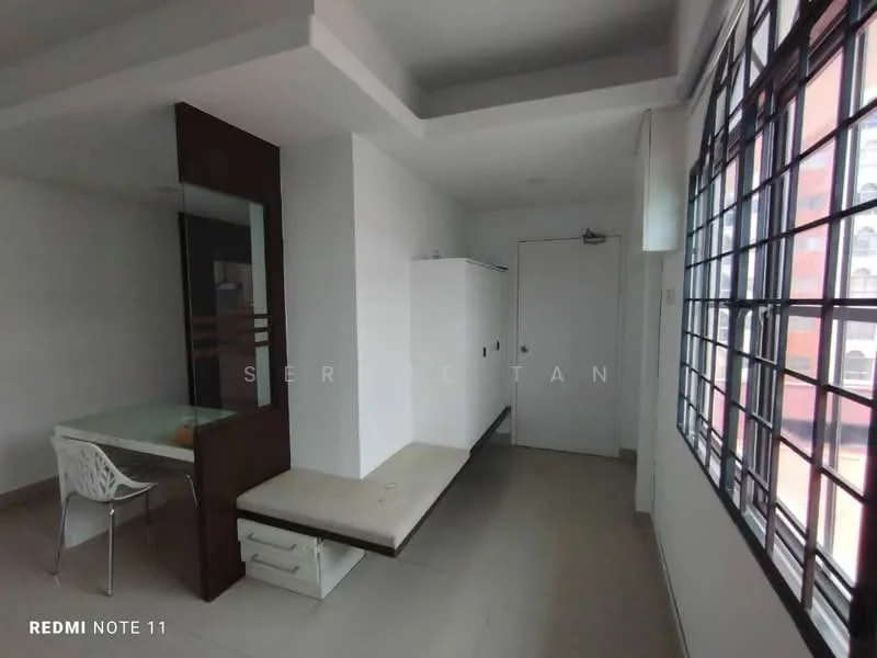 Room features: white painted walls, grey tiled flooring, large windows with black metal frames, built-in white cabinetry, desk with glass top, white plastic chair, door with handle, light ceiling, open space layout; style: modern.