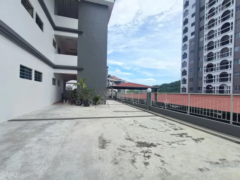 Exterior type: low-rise apartment block; features: concrete flooring, covered walkway, landscaped area with plants, guard rail, adjacent building with balconies, open space, skyline view in background; style: modern.