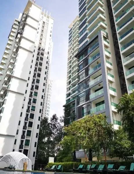 Exterior type: high-rise condominium; features: glass curtain wall, white painted facade, recessed balconies, vertical fins, manicured lawn, surrounded by mature greenery, swimming pool deck with loungers; style: modern.
