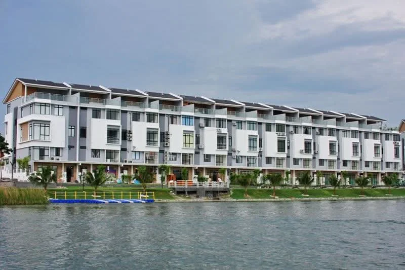 Exterior type: linked terrace house; features: white painted facade, flat roof, 2-storey, balconies on upper floor, large windows, solar panels on roof, manicured lawn, waterfront view, paved walkway, surrounded by greenery; style: modern.