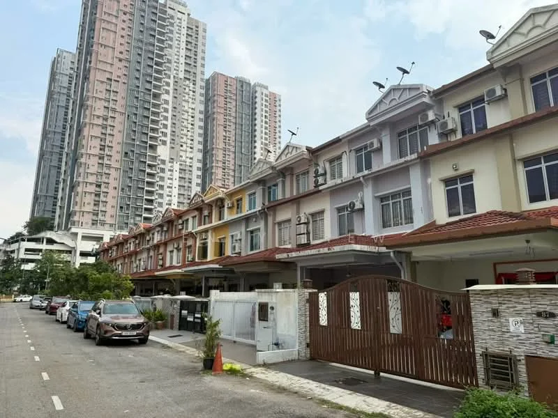 Exterior type: linked terrace house; features: multi-storey buildings in background, row of terrace houses, gated entrance, driveway with interlocking pavers, manicured lawn, parking spaces along the street, red tiled roof, varied facade colors, balconies on upper floors, visible air conditioning units; style: modern.