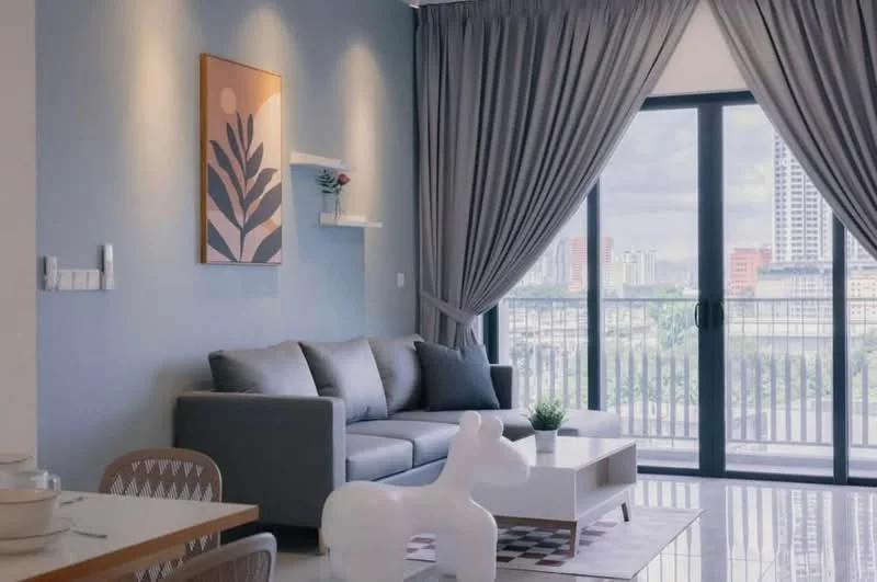 Living features: grey fabric sofa, white coffee table, area rug with geometric pattern, floor-to-ceiling windows, sheer curtains, decorative wall art, wall-mounted shelf, decorative plant, city view, light-colored walls, polished tile flooring; style: modern; view: city.