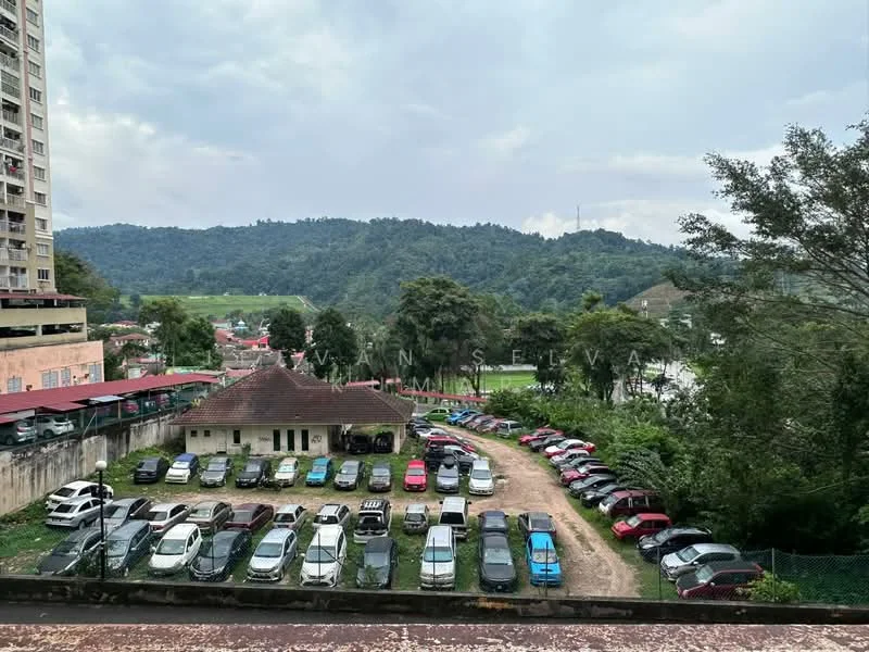 Exterior type: mid-rise condominium; features: view of surrounding hills, open-air parking lot, landscaped greenery, multiple parked cars, residential buildings in background, partially cloudy sky; style: modern.