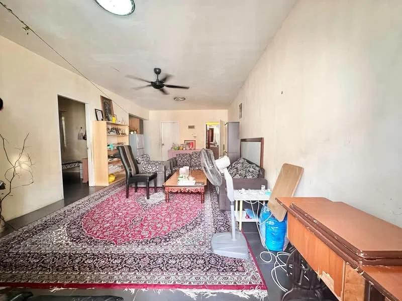 Living features: 3-seater fabric sofa in grey, area rug with intricate pattern, coffee table, ceiling fan, wall-mounted fan, wooden side table, built-in shelving unit, decorative branches in vase, light-colored painted walls, dark flooring.