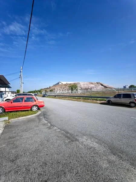 Exterior features: clear blue sky, paved road, gravel hill in background, fenced area, parked cars, greenery along the roadside.