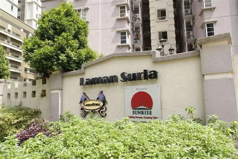 Exterior type: low-rise apartment block; features: signage with 'Laman Suria', landscaped garden with greenery, surrounding residential buildings, lampposts, decorative wall, entrance gate; style: modern.