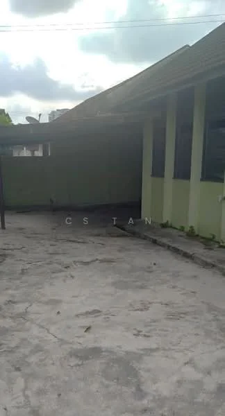 Exterior features: concrete flooring, green painted walls, sloped roof, overcast sky, surrounding greenery, open space.