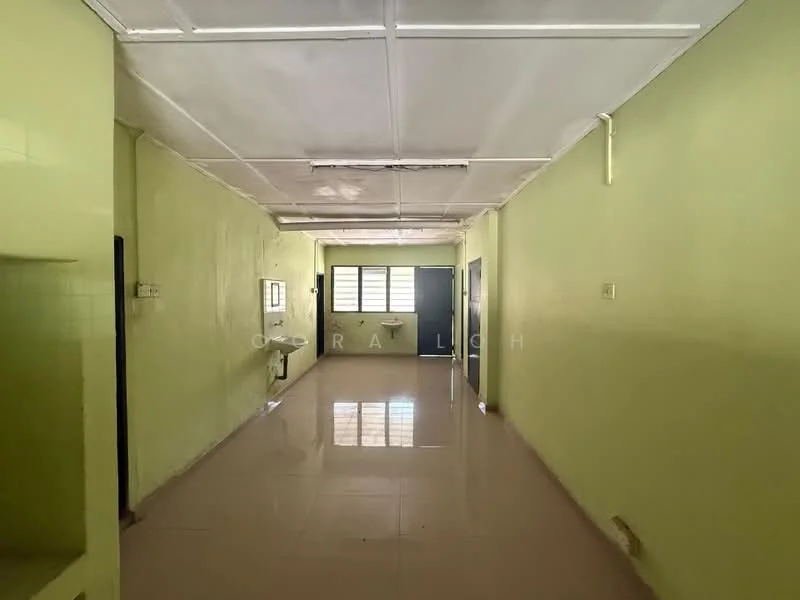 Room features: green painted walls, glossy tile flooring, ceiling with grid tiles, windows with natural light, open layout, no visible furniture, light fixtures on ceiling, doorway leading to another room.