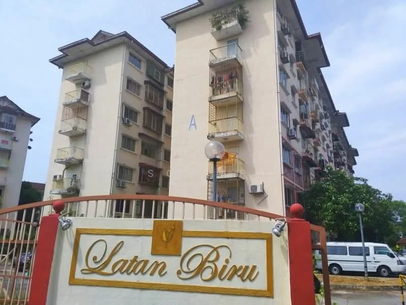 Exterior type: low-rise apartment block; features: cream painted facade, recessed balconies, multiple air conditioning units visible, lamppost at entrance, signage with name 'Latan Biru', surrounding greenery, parking area visible, two-storey building; style: modern.