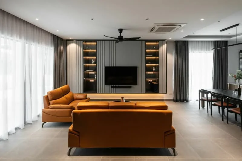 Living features: 3-seater leather sofa in orange, 2-seater leather sofa in orange, wall-mounted TV, built-in shelving with lighting, recessed downlights, ceiling fan, grey tiled flooring, floor-to-ceiling windows with sheer curtains, dark grey curtains, dining table with chairs, decorative items on shelves; style: modern.