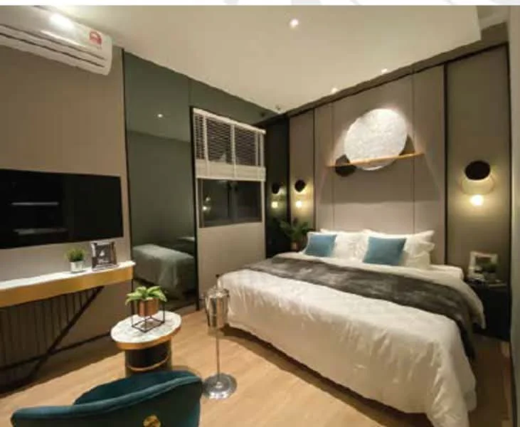 Bedroom features: king-size bed with white bedding, upholstered headboard, 2 bedside lamps, wall-mounted TV, floating shelf above bed, mirrored wardrobe, wooden flooring, air conditioning unit, decorative wall art, greenery in ceramic pot, small round coffee table, accent chair in teal, recessed lighting, blackout curtains; style: modern.