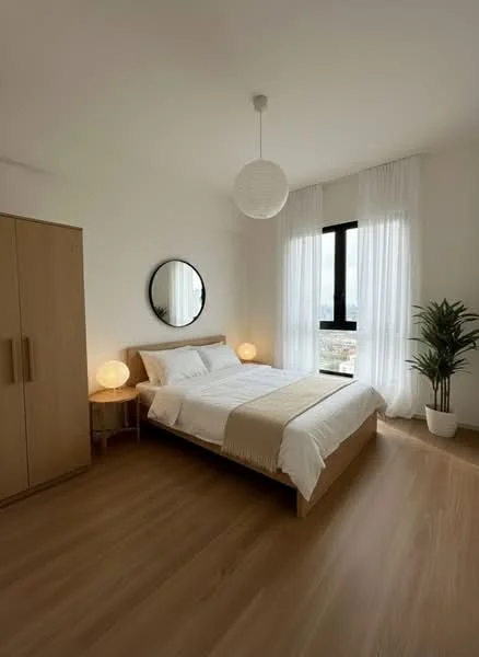 Bedroom features: queen-size bed with white bedding, wooden bed frame, round mirror on wall, two bedside lamps with round bases, wooden bedside table, large window with black frame, sheer white curtains, indoor plant in white pot, light wood flooring, minimalist decor; style: modern; view: city.