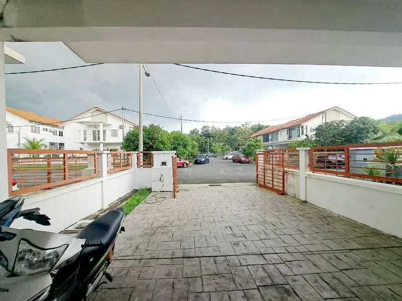Exterior type: linked terrace house; features: paved driveway, metal gate, surrounding greenery, parking area, two-storey houses in background, street lighting, fenced perimeter, concrete walls, manicured landscaping; style: modern.