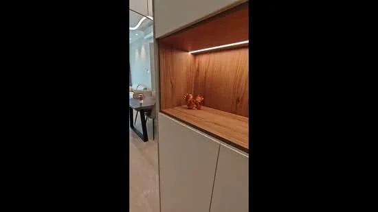 Room features: built-in cabinetry with wood accents, light wood shelving, ambient lighting, decorative figurines, light-colored wall panels, smooth flooring, open layout, modern design; style: modern.