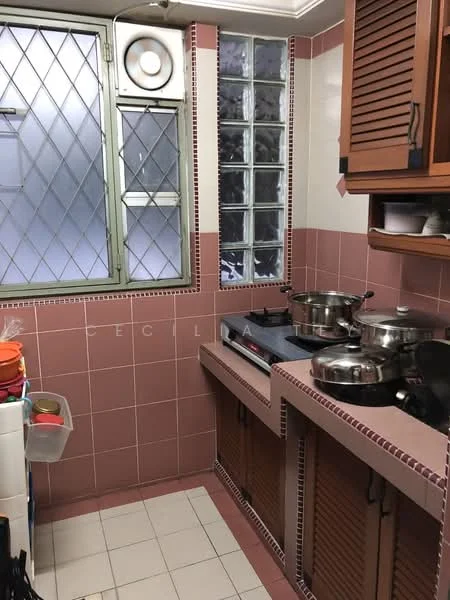 Kitchen features: pink tiled walls, white tiled flooring, brown wooden cabinetry, stainless-steel gas stove, stainless-steel pots, glass block windows, exhaust fan, countertop with backsplash, open shelving, various colored utensils.