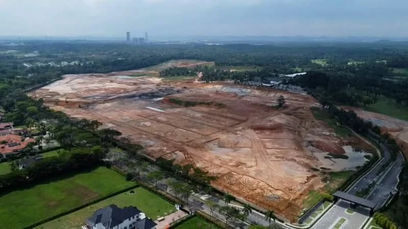 Exterior type: land development site; features: cleared land, earthworks in progress, surrounding greenery, road access, nearby residential properties, open space, distant city skyline.