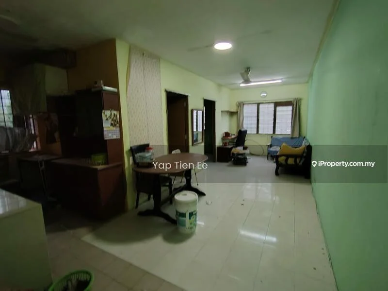 Room features: green painted walls, white ceiling, tile flooring, large windows with natural light, wooden dining table, single sofa, plastic bucket, unfurnished space, curtains, wall-mounted light fixture.