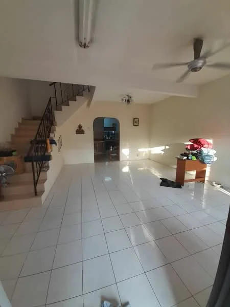 Living features: white painted walls, glossy ceramic tile flooring, 5-blade ceiling fan, large arched doorway, staircase with metal railing, natural light from windows, decorative wall art, furniture including a wooden table, various items stacked on the floor.