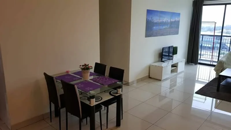 Dining features: glass dining table, 4 black dining chairs, purple placemats, decorative potted plant, white TV console, wall-mounted TV, large window with balcony access, cream painted walls, glossy tile flooring, area rug, framed artwork on wall; style: modern; view: city.