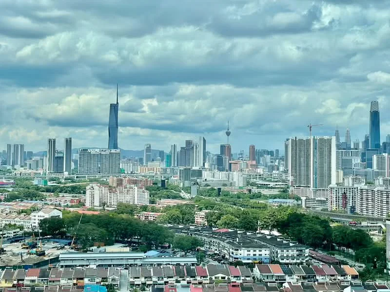 Exterior type: high-rise condominium; features: city skyline view, mixed-use urban landscape, tall skyscrapers, green parks, residential buildings, commercial buildings, construction cranes, cloudy sky, urban greenery; style: modern.