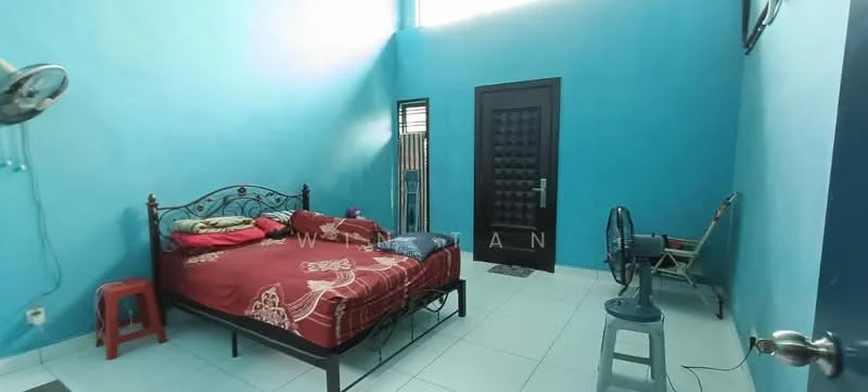 Bedroom features: blue painted walls, white tile flooring, queen-size bed with red bedding, metal bed frame, single bedside stool, wall-mounted ceiling fan, door with textured panel, window with security bars, plastic chair, small stool.
