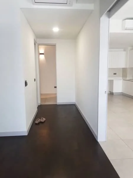 Hallway features: white painted walls, dark wood flooring, recessed downlights, air conditioning unit, doorway leading to kitchen, doorway leading to another room, slippers on the floor; style: modern.