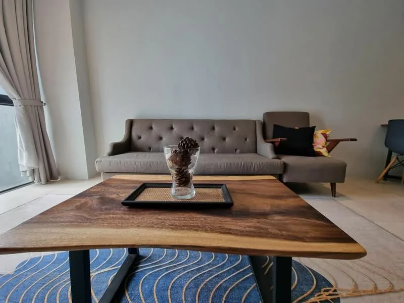 Living features: grey fabric sofa with tufted design, wood coffee table with natural finish, decorative glass vase with pinecones, area rug with wave pattern, floor-to-ceiling windows, curtains in light fabric, accent chair with wooden legs, wall with neutral paint; style: modern.