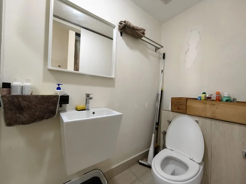 Bathroom features: white wall-mounted sink, chrome basin mixer faucet, framed mirror, one-piece toilet, beige tiled flooring, wooden shelf with toiletries, towel rack, cleaning supplies, soap dispenser, toiletries on shelf; style: modern.