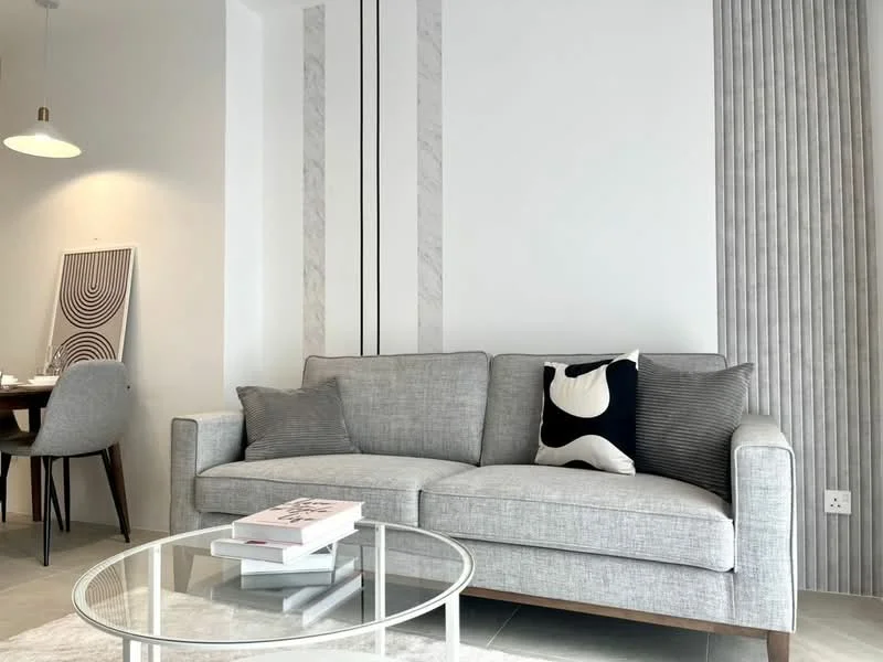Living features: grey fabric 3-seater sofa, black and white decorative cushion, glass coffee table, white walls, striped feature wall, marble accent wall, pendant light fixture, area rug, dining area visible in background, floor-to-ceiling windows, light grey tiled flooring; style: modern.