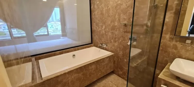 Bathroom features: freestanding bathtub, glass shower enclosure, single-sink vanity with countertop, chrome basin mixer faucet, marble tile flooring, marble wall cladding, large window with sheer curtains, built-in shelving, wall-mounted mirror; style: modern; view: city.