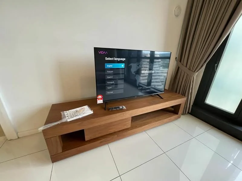 Living features: flat-screen TV on wooden console, wooden TV console, remote control on console, white walls, cream curtains, floor-to-ceiling windows, glossy tile flooring, natural light from windows; style: modern.