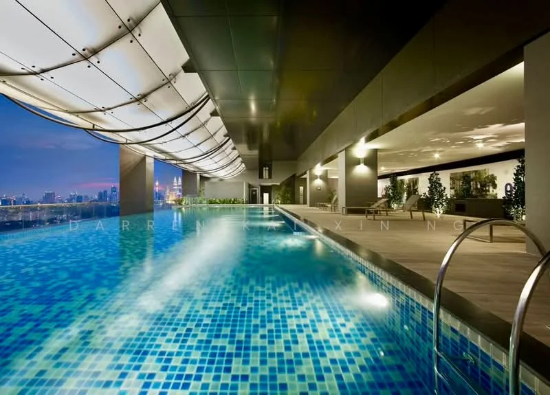 Exterior type: high-rise condominium; features: infinity pool, pool deck with loungers, glass railing, tiled pool surface with blue mosaic tiles, landscaped area with potted plants, night lighting, city skyline view, overhanging roof structure; style: modern.