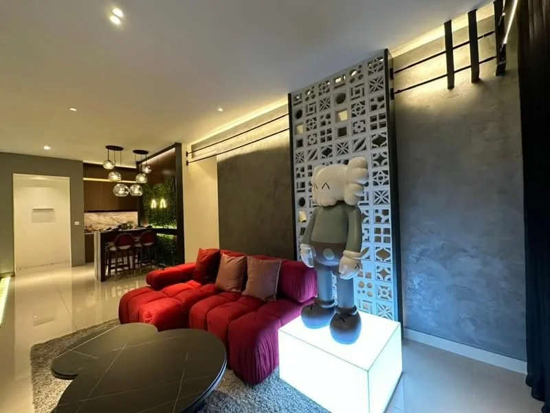 Living features: red fabric sectional sofa, black coffee table, decorative figure on pedestal, grey accent wall, recessed lighting, pendant lights, glossy tile flooring, open layout to kitchen, wall art or decorative panel, plant decor; style: modern.
