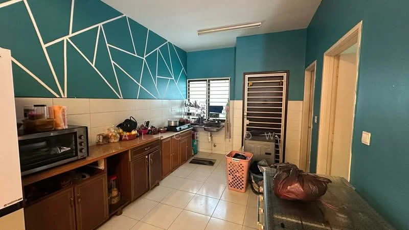 Kitchen features: blue accent wall with geometric pattern, white tiled walls, white tile flooring, wood cabinetry with brown finish, stainless-steel sink, chrome faucet, microwave, countertop with food preparation items, laundry basket, kitchen appliances on countertop, window with metal grille, door leading to another room; style: modern.