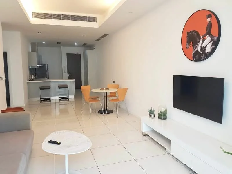 Living features: white painted walls, glossy white tile flooring, sofa in light grey fabric, round dining table with black base, 4 orange dining chairs, wall-mounted flat-screen TV, white TV console, decorative plant on console, artwork featuring a horse, recessed ceiling lights, open kitchen area visible; style: modern.