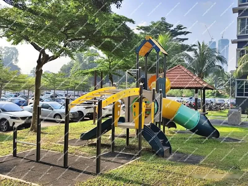 Exterior type: landscape garden; features: children's playground with slide, climbing structure, rubberized safety flooring, manicured lawn, surrounding trees, parking lot visible, pavilion with roof, adjacent to residential building; style: modern.