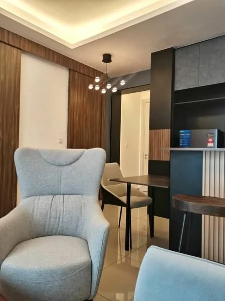 Room features: grey upholstered armchair, wooden side table, black cabinetry, wood paneling, recessed ceiling lights, modern pendant light fixture, glossy tiled flooring, neutral wall color; style: modern.
