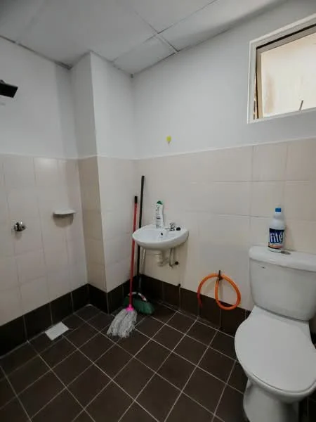 Bathroom features: white tiled walls, cream tiled walls, dark ceramic tile flooring, toilet, sink, mop, broom, cleaning supplies, window, wall-mounted faucet, soap dispenser.
