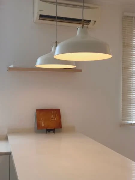Kitchen features: white walls, light-colored countertop, suspended pendant lights, 1 wall-mounted split AC, open shelving, blinds on windows, minimalist decor; style: modern.