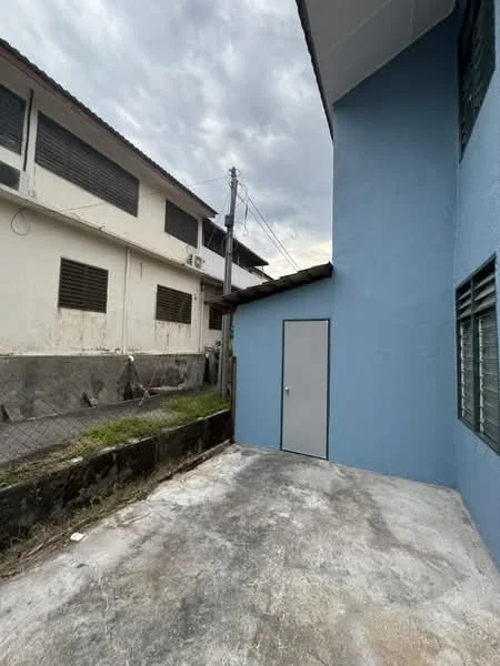 Exterior features: blue painted wall, concrete flooring, fenced area, adjacent buildings, utility poles visible, grey cloudy sky.