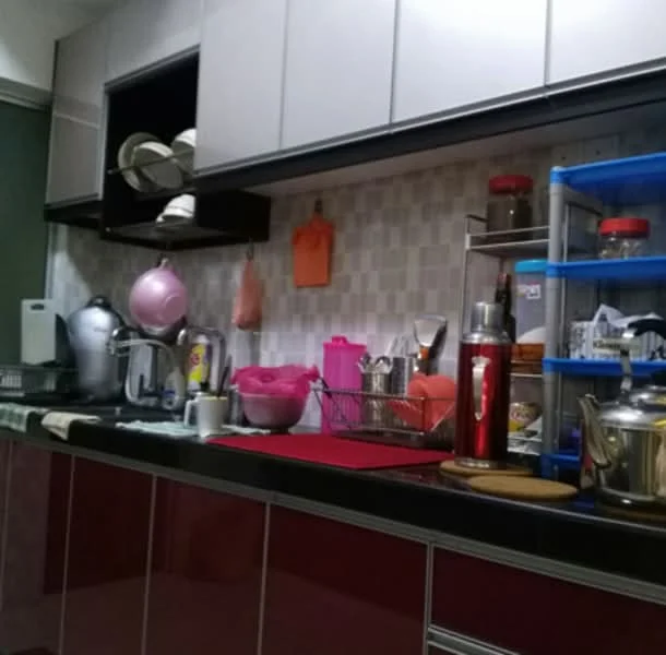 Kitchen features: black countertop, red cabinetry, grey tiled backsplash, stainless-steel kettle, white electric kettle, glass jars on shelves, pink bowl, metal utensils, dish rack, plastic storage containers, sink, wall-mounted storage, cooking utensils, appliance storage, open shelving; style: modern.