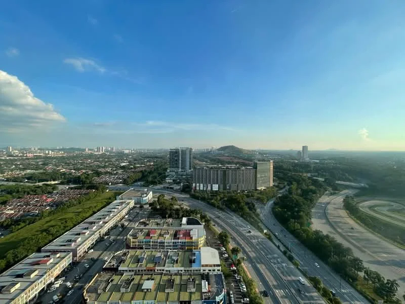 Exterior type: high-rise condominium; features: city skyline view, surrounded by greenery, adjacent to highway, multi-storey buildings in the background, open road, hills in the distance; style: modern.