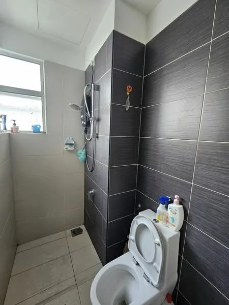Bathroom features: white toilet, shower with handheld showerhead, grey tiled walls, light grey tiled flooring, window for natural light, toiletries on shelf, shower valve, wall-mounted soap dispenser; style: modern.